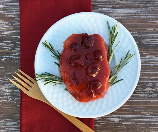 Pork Chop on plate with cranberry sauce.