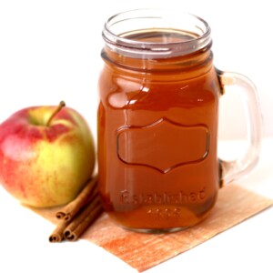 Apple and cinnamon sticks next to a jar of apple cider.