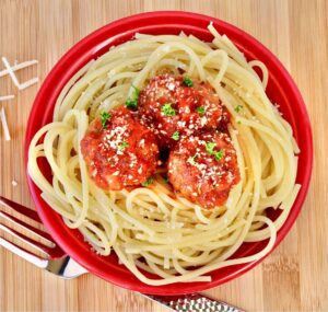 Meatballs with red sauce over noodles.