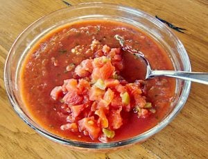 Spoon scooping salsa from a bowl.
