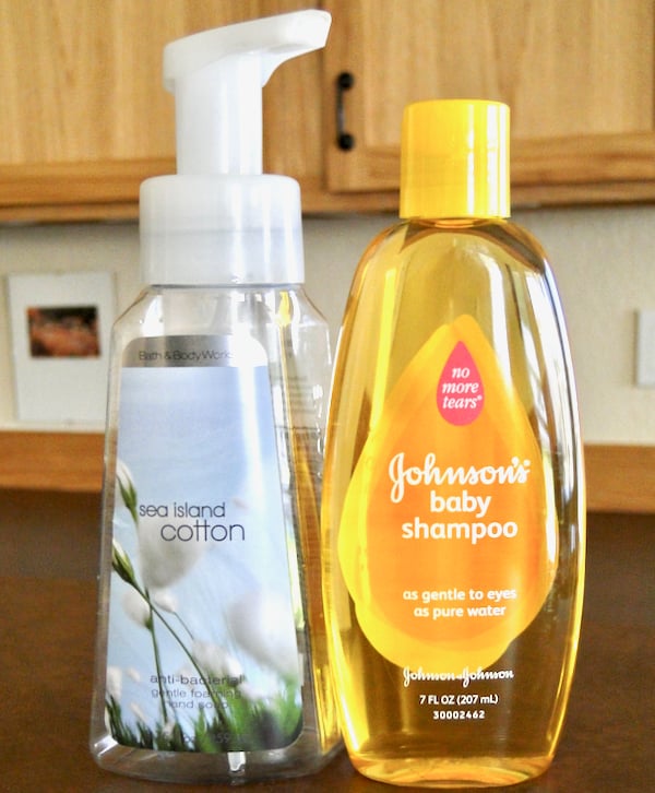 Bottle of shampoo next to empty foaming soap container.