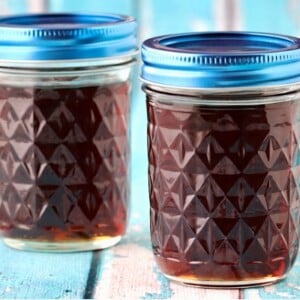 Two mason jars with blue lids filled with homemade syrup.