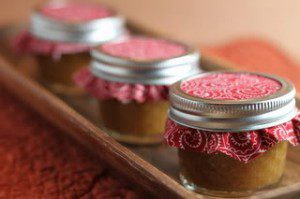Jars in a line on a wooden tray.