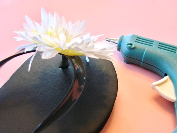 Gluing silk flower onto flip flop.
