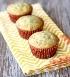 Three banana bread muffins on a yellow chevron napkin.