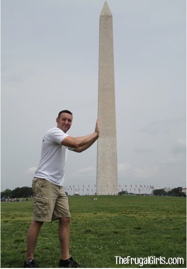 Man looking like he is pushing on the Washington Monument.
