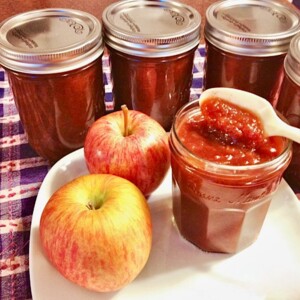Spoon in a jar of Apple Butter with apples.