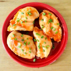 Apricot chicken on a red plate.