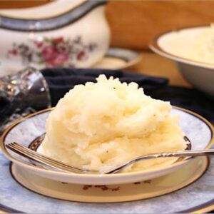Mashed Potatoes piled on a plate with fork.