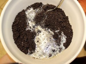 Spoon mixing melted butter into Oreo crumbles.