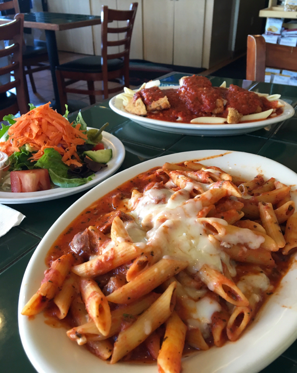 Baked ziti on plate with side salad.