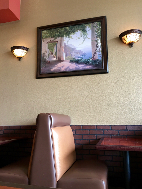Restaurant booth and artwork on wall.