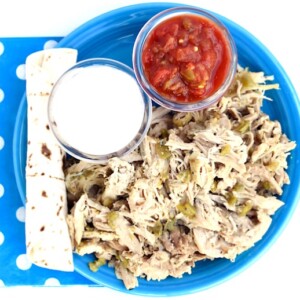 Green Chile Chicken on a blue plate with dips.