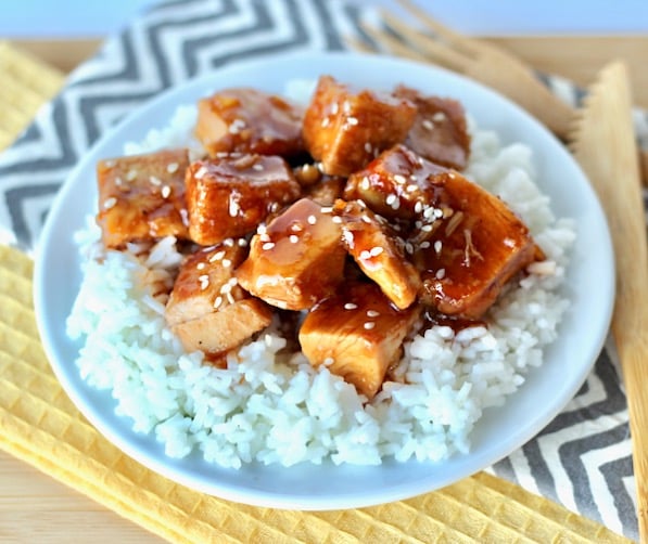 Cubed orange chicken on a plate with rice.