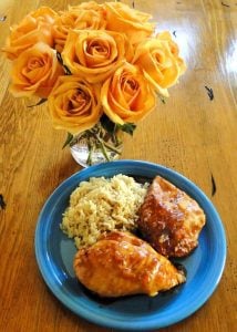 Orange Chicken and Rice on a plate next to flowers.