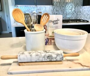 Baking items such as a rolling pin and wooden spoons on an counter.
