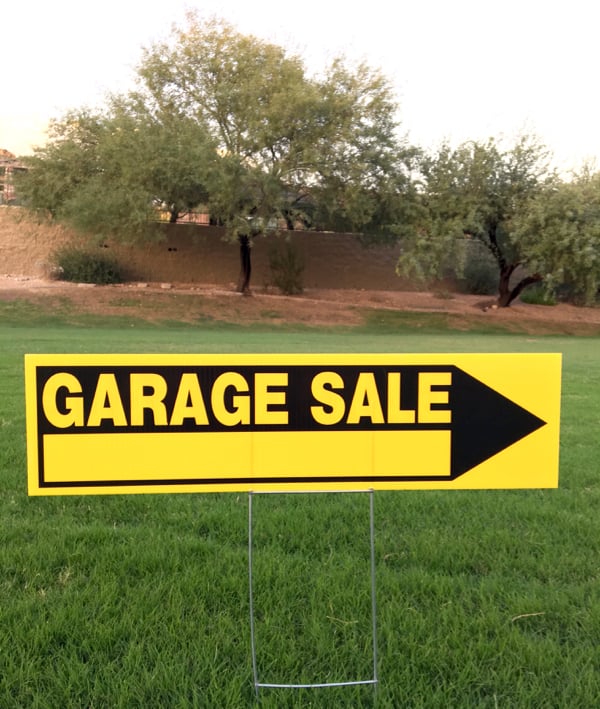 Garage sale sign with arrow in grass.