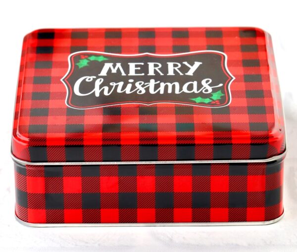 A red and black checkered cookie tin with Merry Christmas printed on top.