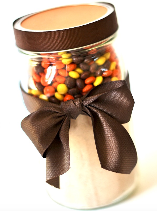 Reese\'s Pieces cookie mix layered in mason jar, with brown bow tied around jar.