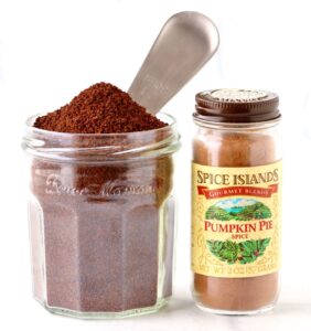 Coffee grounds in jar with coffee scoop and a pumpkin spice jar.