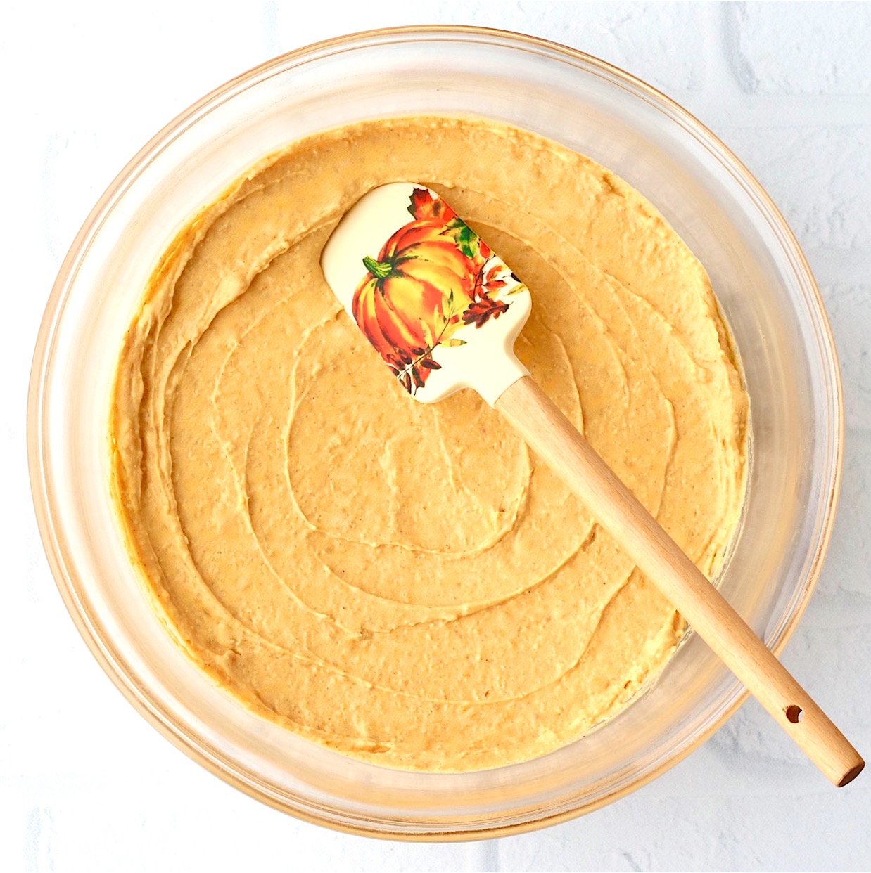 Pumpkin Dip stirred in a glass bowl with pumpkin spatula.
