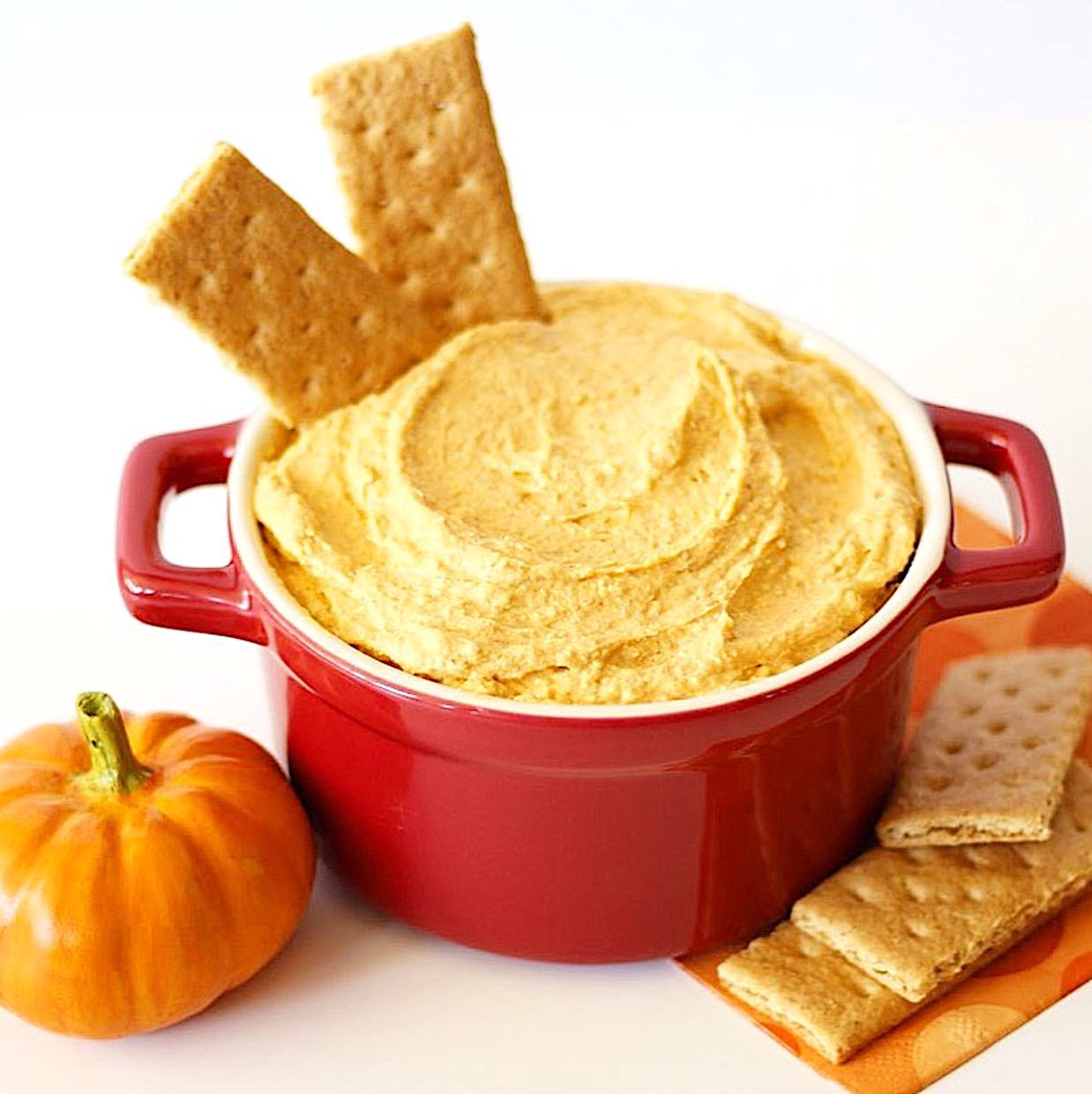 Pumpkin dip in a red bowl with graham crackers.