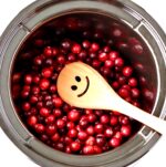 Cranberry sauce in crock pot with wooden spoon.