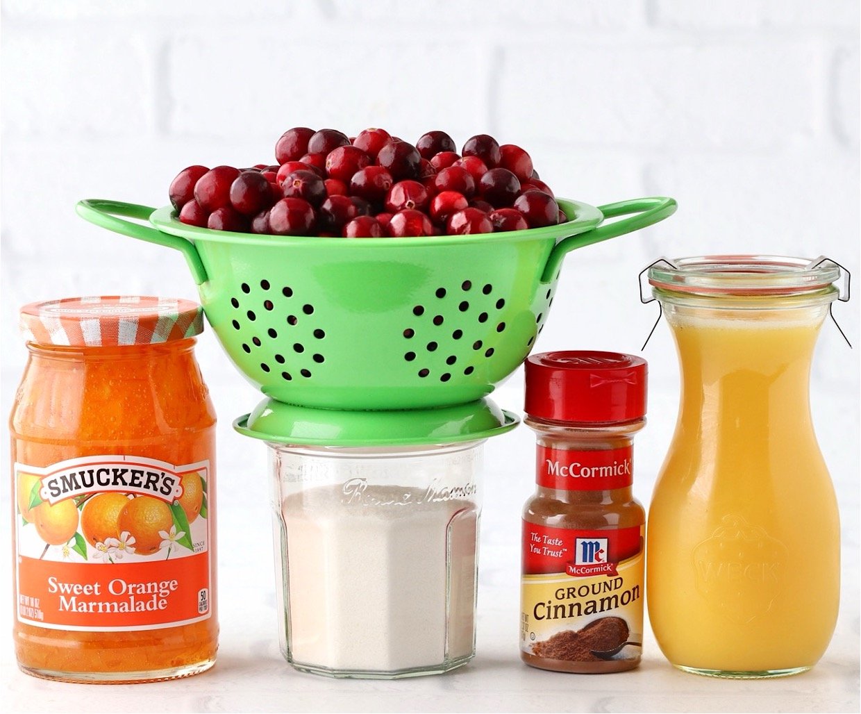 Ingredients for homemade cranberry sauce including orange marmalade, cinnamon, and cranberries.
