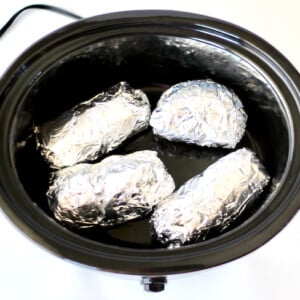 Foil-wrapped sweet potatoes in a slow cooker.