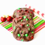 Three chocolate M&M Christmas cookies on a napkin.