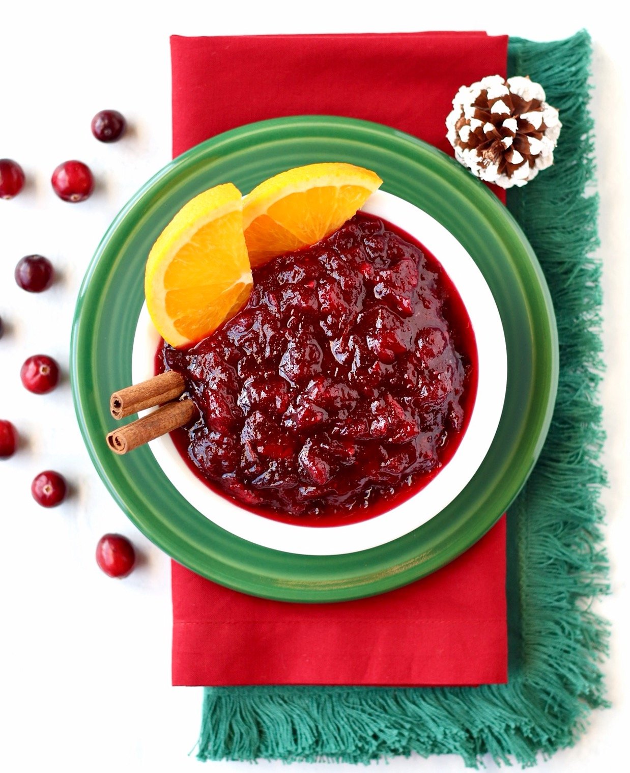 Homemade fresh cranberry sauce in dish with cinnamon sticks.