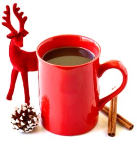 Cinnamon coffee in mug with cinnamon sticks, pinecone, and reindeer figurine.