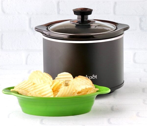 Potato chips in dish in front of mini crockpot with crab dip.