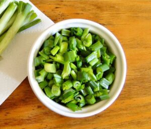 Chopped green onions in a small white bowl.