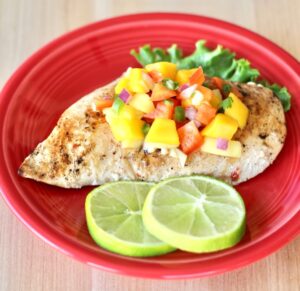 Grilled chicken breast on plate with pineapple mango salsa on top.