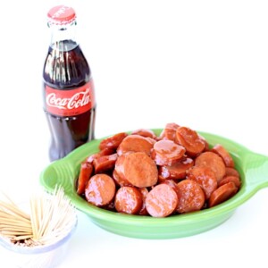 Slices of kielbasa in a bowl next to a bottle of Coke.