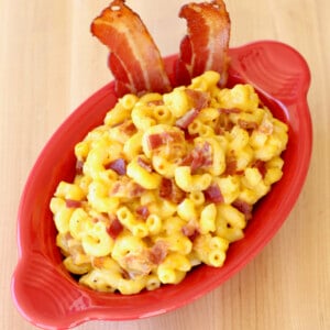 Red bowl of bacon macaroni and cheese.