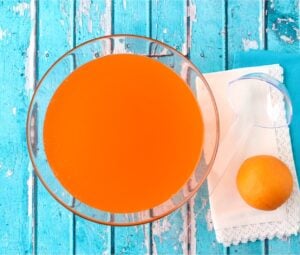 Orange punch in punch bowl with ladle and orange to the side.