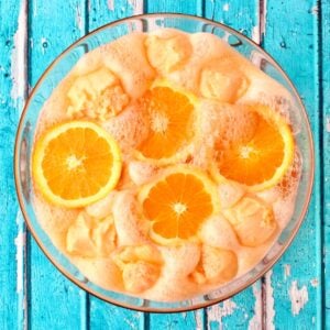 Orange Punch in glass punch bowl with scoops of sherbet and orange slices.