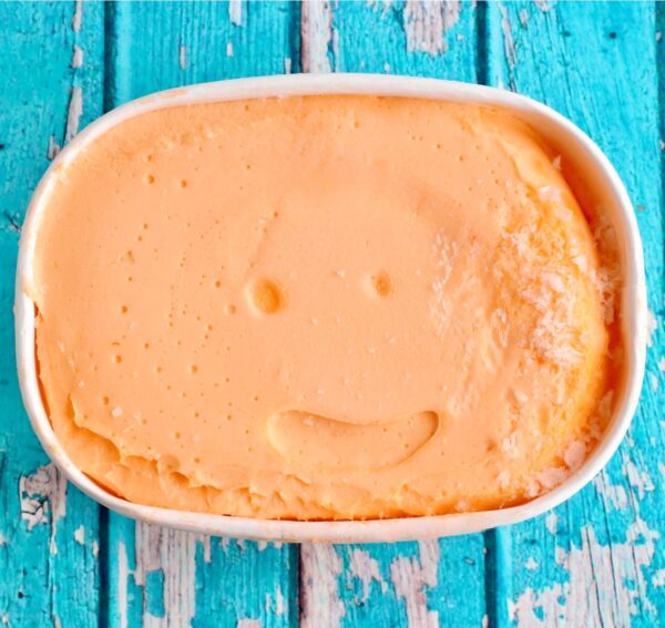 Orange sherbet in carton with lid off.