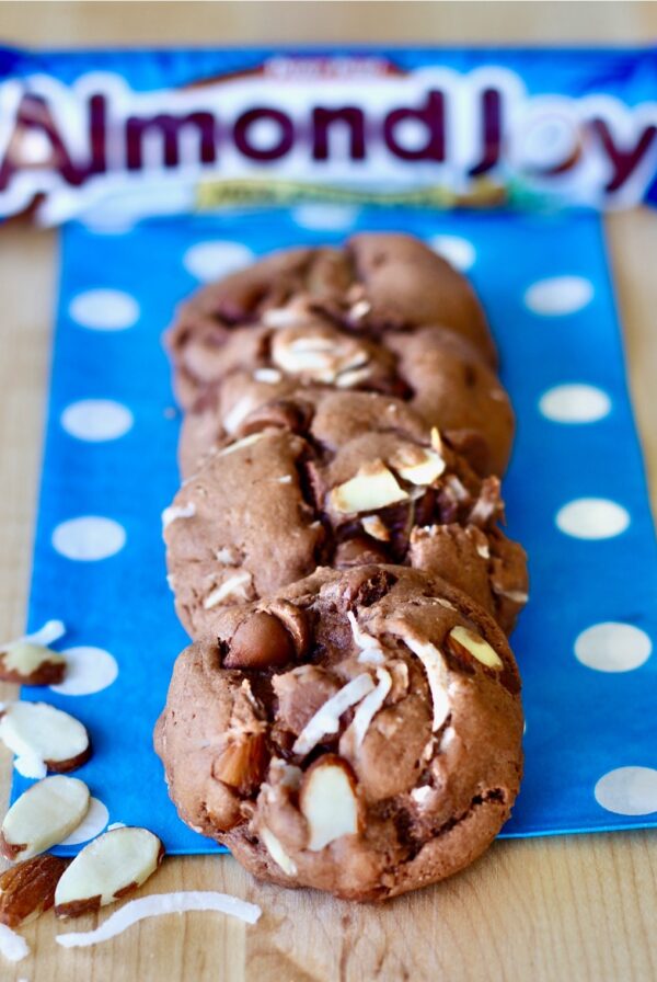 Three Almond Joy Cookies on napkin, with Almond Joy candy bar behind.