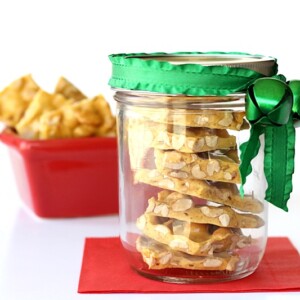 Peanut Brittle in a jar tied with a green ribbon.