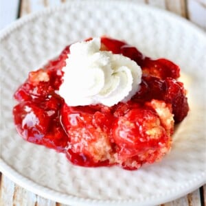 Strawberry Dump Cake with whipped cream on a plate.