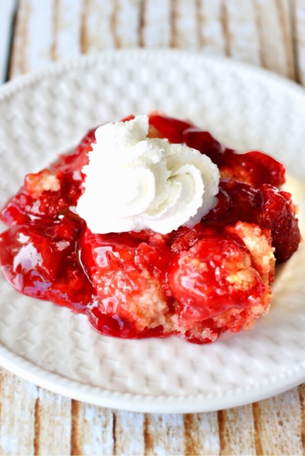 Strawberry Dump Cake with whipped cream on a plate.