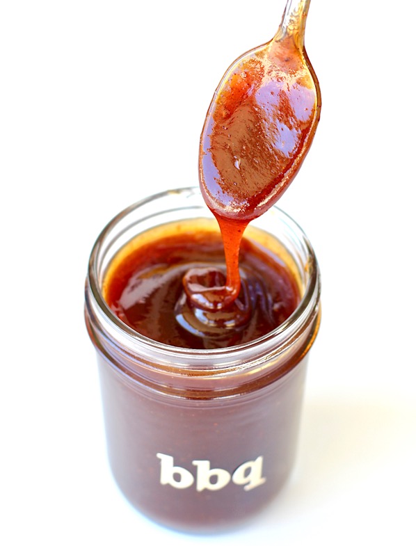 Barbecue sauce falling off spoon into mason jar.
