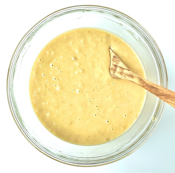 Wooden spoon in a bowl of Banana Bread Muffin batter.