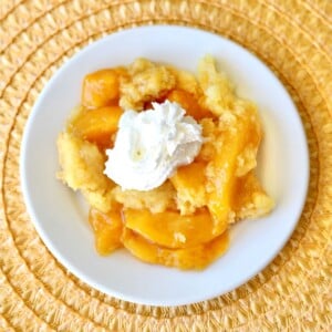 Peach Dump Cake stopped with whipped cream.