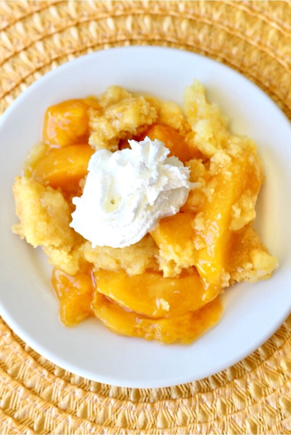Peach Dump Cake stopped with whipped cream.
