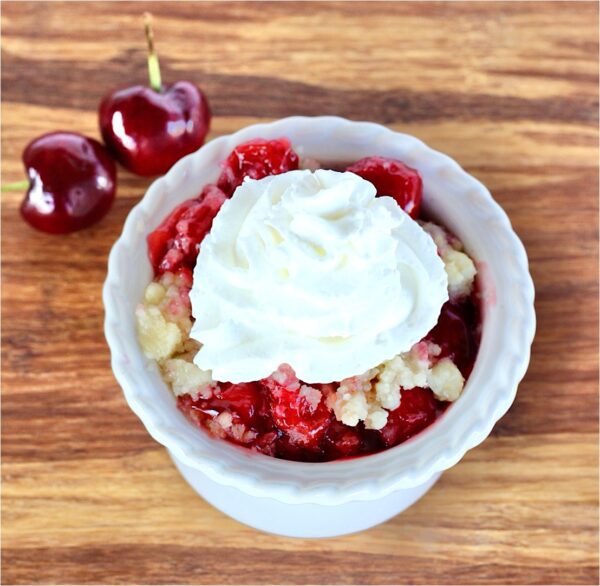 Cherry Dump Cake topped with whipped cream.