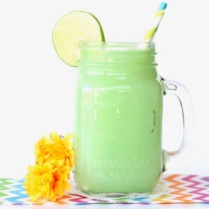 Jar of lime sherbet party punch with a lime slice.